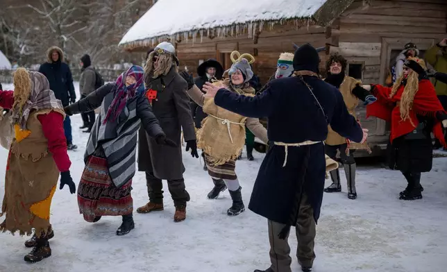 Revelers wearing traditional carnival masks dance during Shrovetide celebrations in the village of Rumsiskes, some 89 kilometers (56 miles) north of Vilnius, Lithuania, Saturday, Feb. 14, 2026. (AP Photo/Mindaugas Kulbis)