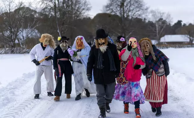 Revellers wearing traditional carnival masks take part in Shrovetide celebrations in the village of Rumsiskes, some 89 kilometers (56 miles) north of Vilnius, Lithuania, Saturday, Feb. 14, 2026. (AP Photo/Mindaugas Kulbis)