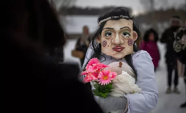 A reveller wearing traditional carnival masks takes part in Shrovetide celebrations in the village of Rumsiskes, some 89 kilometers (56 miles) north of Vilnius, Lithuania, Saturday, Feb. 14, 2026. (AP Photo/Mindaugas Kulbis)