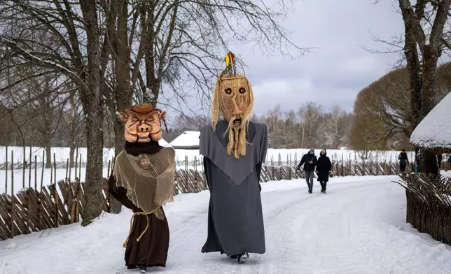 Revellers wearing traditional carnival masks take part in Shrovetide celebrations in the village of Rumsiskes, some 89 kilometers (56 miles) north of Vilnius, Lithuania, Saturday, Feb. 14, 2026. (AP Photo/Mindaugas Kulbis)