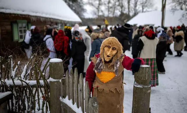 A woman wearing a traditional carnival mask takes part in Shrovetide celebrations in the village of Rumsiskes, some 89 kilometers (56 miles) north of Vilnius, Lithuania, Saturday, Feb. 14, 2026. (AP Photo/Mindaugas Kulbis)