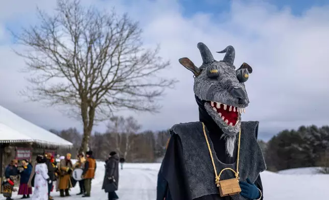A man wearing traditional carnival masks takes part in Shrovetide celebrations in the village of Rumsiskes, some 89 kilometers (56 miles) north of Vilnius, Lithuania, Saturday, Feb. 14, 2026. (AP Photo/Mindaugas Kulbis)