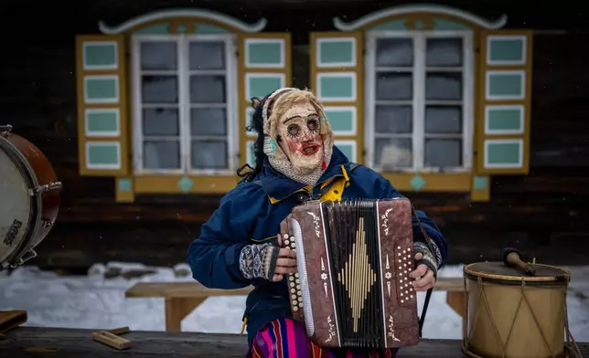 A woman wearing traditional carnival masks takes part in Shrovetide celebrations in the village of Rumsiskes, some 89 kilometers (56 miles) north of Vilnius, Lithuania, Saturday, Feb. 14, 2026. (AP Photo/Mindaugas Kulbis)