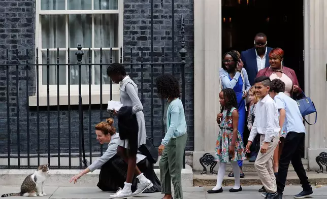 FILE - School children approach Downing Street chief mouser Larry the cat, as they leave after a scheduled meeting with Britain's Prime Minister Boris Johnson at 10 Downing Street in London, Friday, Aug. 30, 2019. (AP Photo/Frank Augstein, File)