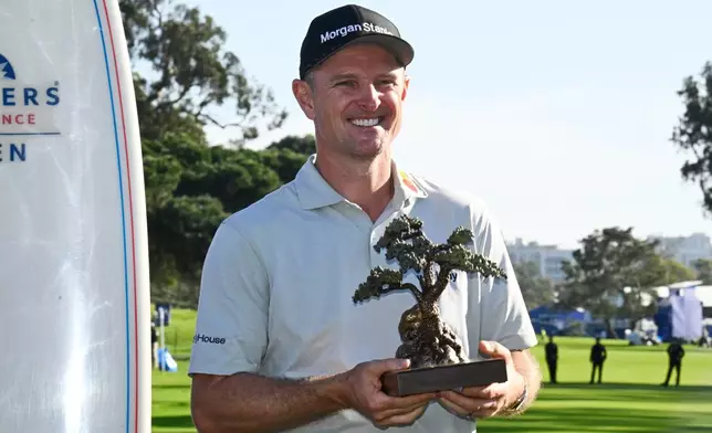 Justin Rose, of England, holds the winner's trophy at the Farmers Insurance Open golf tournament Sunday, Feb. 1, 2026, at Torrey Pines in San Diego. (AP Photo/Denis Poroy)