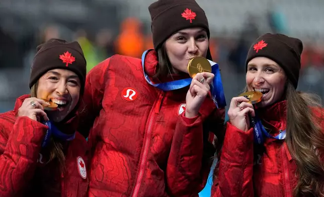 Team Canada with Isabelle Weidemann, center, Valerie Maltais, left, and Ivanie BLondin, right, celebrate winning the gold medal in the final of the women's team pursuit speedskating race at the 2026 Winter Olympics, in Milan, Italy, Tuesday, Feb. 17, 2026. (AP Photo/Ben Curtis)
