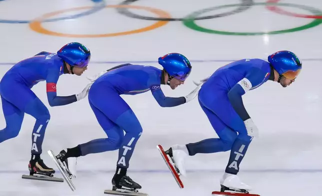 Team Italy with Davide Ghiotto, white armband, Andrea Giovannini, red armband, and Michele Malfatti, blue armband, compete to win the gold medal in the final of the men's team pursuit speedskating race at the 2026 Winter Olympics, in Milan, Italy, Tuesday, Feb. 17, 2026. (AP Photo/Luca Bruno)