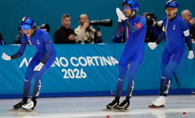 Team Italy with Michele Malfatti, left, Andrea Giovannini, center, and Davide Ghiotto, right, celebrate winning the gold medal in the final of the men's team pursuit speedskating race at the 2026 Winter Olympics, in Milan, Italy, Tuesday, Feb. 17, 2026. (AP Photo/Ben Curtis)