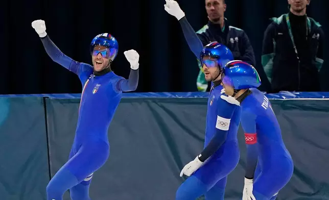 Team Italy with Davide Ghiotto, white armband, Andrea Giovannini, red armband, and Michele Malfatti, blue armband, celebrate after winning the semifinal of the men's team pursuit speedskating race at the 2026 Winter Olympics, in Milan, Italy, Tuesday, Feb. 17, 2026. (AP Photo/Ben Curtis)