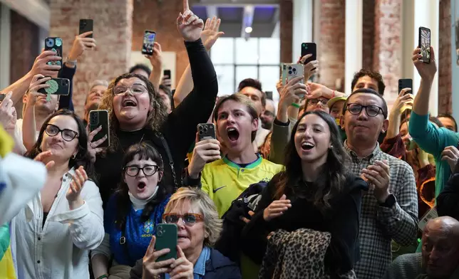 Supporters of Brazil's Lucas Pinheiro Braathen react at the Brazil House as he starts his second run in the men's giant slalom at the 2026 Winter Olympics, in Milan, Italy, Saturday, Feb. 14, 2026. (AP Photo/Antonio Calanni)