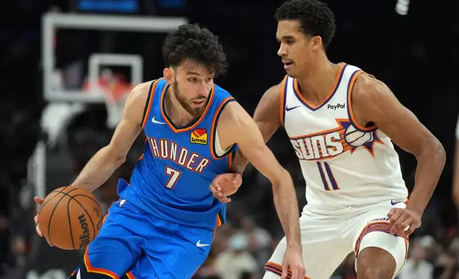 Oklahoma City Thunder center Chet Holmgren (7) drives on Phoenix Suns forward Oso Ighodaro during the first half of an NBA basketball game, Wednesday, Feb. 11, 2026, in Phoenix. (AP Photo/Rick Scuteri)