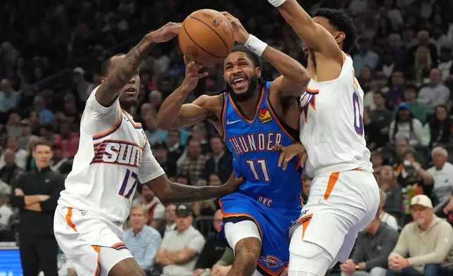 Oklahoma City Thunder guard Isaiah Joe drives between Phoenix Suns guard Amir Coffey (17) and forward Ryan Dunn during the first half of an NBA basketball game, Wednesday, Feb. 11, 2026, in Phoenix. (AP Photo/Rick Scuteri)