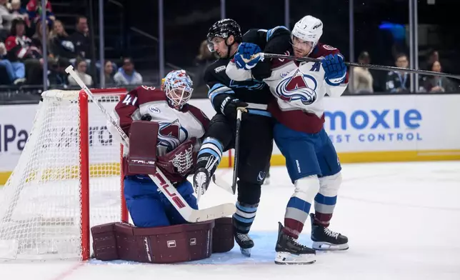 Colorado Avalanche goaltender Scott Wedgewood, left, makes the save on the tipped shot from Utah Mammoth center Alexander Kerfoot, center, as he is pushed away from the net by Colorado Avalanche defenseman Devon Toews, right, during the second period of an NHL hockey game, Wednesday, Feb. 25, 2026, in Salt Lake City. (AP Photo/Tyler Tate)