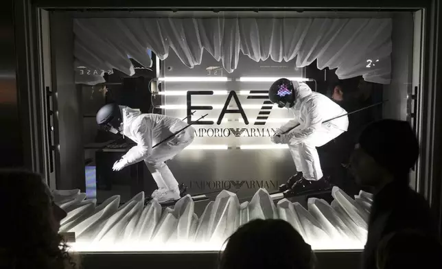 FILE - People watch the shop window during an event celebrating the Milan Cortina 2026 Winter Olympics at the Emporio Armani store during the Fall/Winter 2026-2027 men's fashion week in Milan, Italy, Jan. 17, 2026. (AP Photo/Antonio Calanni, File)