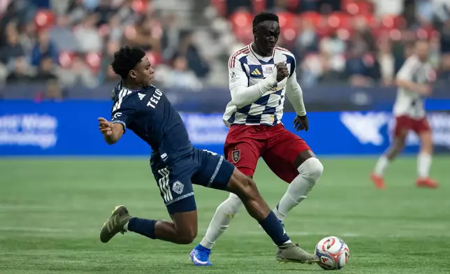 Vancouver Whitecaps' Ralph Priso (left) and Real Salt Lake's Ariath Piol (19) vie for the ball during the first half of an MLS soccer match in Vancouver, on Saturday, Feb. 21, 2026. (Ethan Cairns/The Canadian Press via AP)