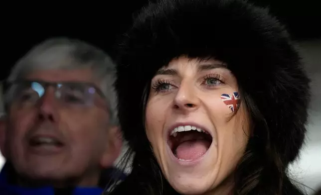 A person cheers during a women's skeleton run at the 2026 Winter Olympics, in Cortina d'Ampezzo, Italy, Friday, Feb. 13, 2026. (AP Photo/Alessandra Tarantino)