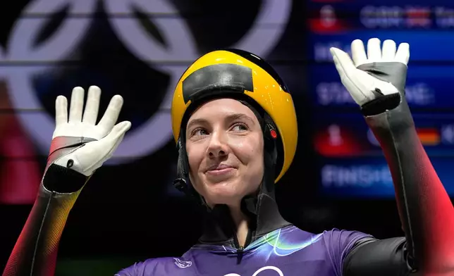 Germany's Susanne Kreher waves as she arrives at the finish during a women's skeleton run at the 2026 Winter Olympics, in Cortina d'Ampezzo, Italy, Friday, Feb. 13, 2026. (AP Photo/Alessandra Tarantino)