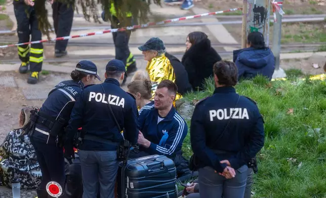 Police officers speak with a man at the scene of a derailment on Line 9 in Milan, Italy, Friday, Feb. 27, 2026. (Stefano Porta/LaPresse via AP)