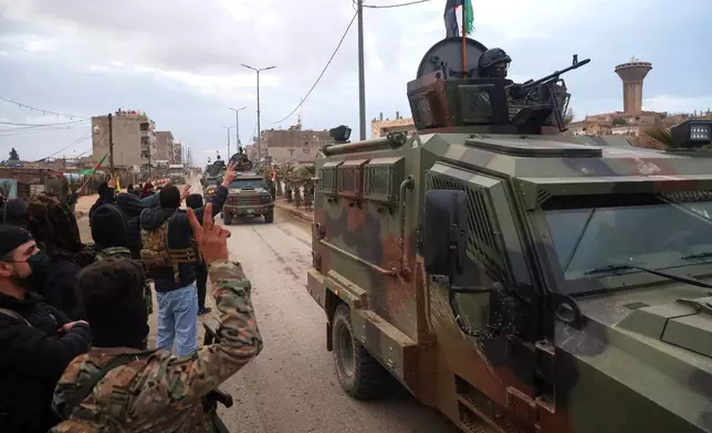 Kurdish-led Syrian Democratic Forces (SDF) combatants welcome the arrival of a convoy Syria's Interior Ministry security forces, deployed under an agreement aimed at stabilizing a ceasefire, in Qamishli, eastern Syria, Tuesday, Feb. 3, 2026. (AP Photo/Baderkhan Ahmad)