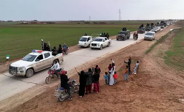Local residents, predominantly Arab, welcome a convoy of Syria's Interior Ministry forces as it passes through en route to the mostly Kurdish town of Qamishli, where the forces are deploying under a ceasefire agreement with the Kurdish-led Syrian Democratic Forces (SDF), near the village of Mazraat al-Nahar, northeastern Syria, Tuesday, Feb. 3, 2026. (AP Photo/Ghaith Alsayed)