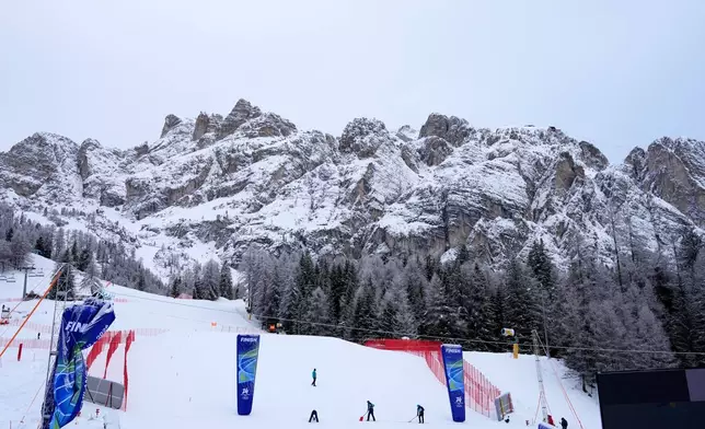 Race officials prepare the course ahead of an alpine ski, women's downhill official training, at the 2026 Winter Olympics, in Cortina d'Ampezzo, Italy, Friday, Feb. 6, 2026. (AP Photo/Giovanni Auletta)