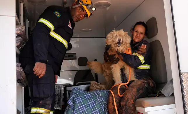 A dog named Lucky is held by firefighters after rescue from the site where homes collapsed due to heavy rains and flooding in the Parque Burnier neighborhood of Juiz de Fora, in Minas Gerais state, Brazil, Wednesday, Feb. 25, 2026. (AP Photo/Silvia Izquierdo)