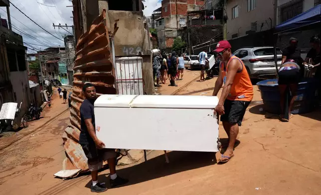 Residents recover belongings after homes collapsed due to heavy rains and flooding in the Parque Burnier neighborhood of Juiz de Fora, Minas Gerais state, Brazil, Wednesday, Feb. 25, 2026. (AP Photo/Silvia Izquierdo)