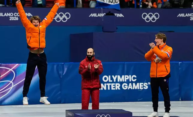 Silver medalist Melle van 't Wout of the Netherlands jumps to the podium to receive his medal after the short track speed skating men's 500m at the 2026 Winter Olympics, in Milan, Italy, Wednesday, Feb. 18, 2026. (AP Photo/Ashley Landis)