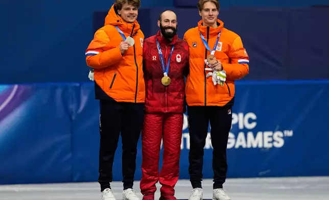 From left to right, silver medalist Melle van 't Wout of the Netherlands, gold medalist Steven Dubois of Canada and bronze medalist Jens van 't Wout of the Netherlands receive their medals after the short track speed skating men's 500m at the 2026 Winter Olympics, in Milan, Italy, Wednesday, Feb. 18, 2026. (AP Photo/Ashley Landis)