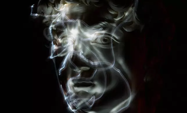 Stefania Terre, who is blind, uses a small light on her fingers while touching a life-size reproduction of the head of Michelangelo's David as she poses for a long-exposure photograph at the Omero Tactile Museum in Ancona, Italy, Thursday, Jan. 15, 2026. (AP Photo/Alessandra Tarantino)