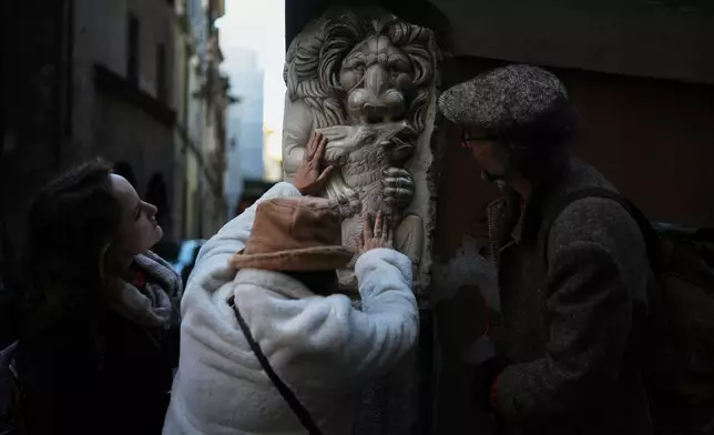 Francesca Inglese, who is blind, touches a marble relief on the corner of a building during an inclusive art tour in downtown Rome, on Nov. 29, 2025. (AP Photo/Alessandra Tarantino)