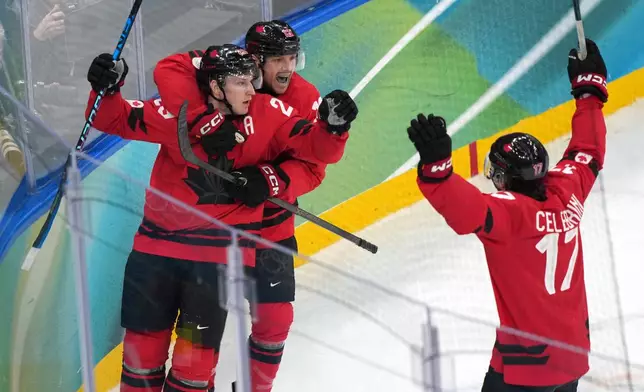 Canada's Nathan MacKinnon (29) celebrates with Sam Reinhart (13) and Macklin Celebrini (17) after MacKinnon scored a goal against Finland during the third period of a men's ice hockey semifinal game at the 2026 Winter Olympics in Milan, Italy, Friday, Feb. 20, 2026. (AP Photo/Carolyn Kaster)