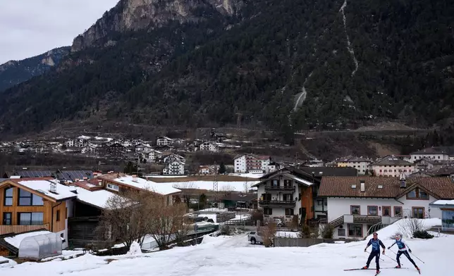 Cross-country skiing athletes from Armenia ski through the village of Ziano di Fiemme during a non-competition day at the 2026 Winter Olympics, near the course in Tesero, Italy, Monday, Feb. 9, 2026. (AP Photo/Armando Franca)