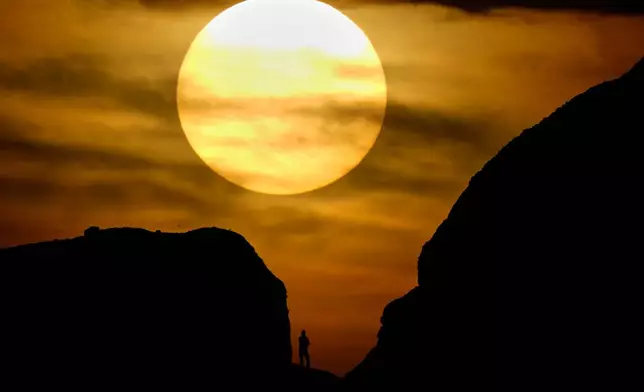 A hiker is silhouetted against the sky at sunset while visiting Papago park in Phoenix on Saturday, Feb. 21, 2026. (AP Photo/Charlie Riedel)
