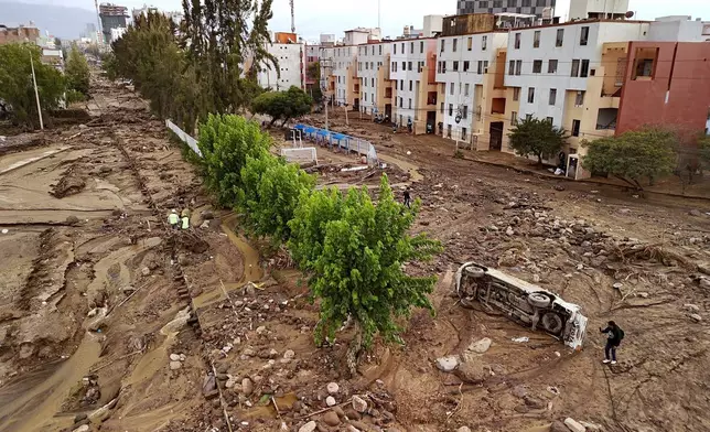 A man takes photos on a destroyed road after heavy rain triggered flooding in Arequipa, Peru, Monday, Feb. 23, 2026. (AP Photo/Jose Sotomayor)