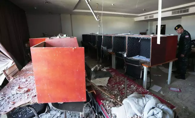 FILE - A Thai soldier inspects a work station with wooden phone booths lined with foam for soundproofing, inside a scam compound in O'Smach, Cambodia, Monday, Feb. 2, 2026. (AP Photo/Sakchai Lalit, File)