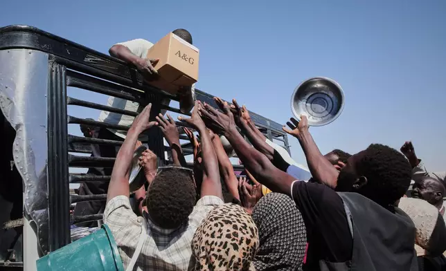 FILE - Sudanese families displaced from El-Fasher reach out as aid workers distribute food supplies at the newly established El-Afadh camp in Al Dabbah, Sudan's Northern State, Nov. 16, 2025. (AP Photo/Marwan Ali, File)