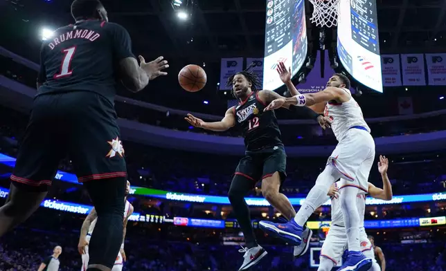 Philadelphia 76ers' Trendon Watford (12) passes Andre Drummond (1) past New York Knicks' Karl-Anthony Towns, right, during the first half of an NBA basketball game Wednesday, Feb. 11, 2026, in Philadelphia. (AP Photo/Matt Rourke)
