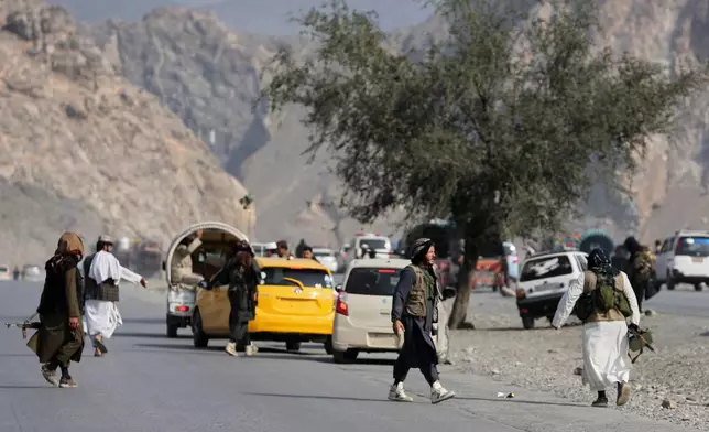 Afghan Taliban soldiers walk on a street as others instruct drivers on the Afghan side of the Torkham border crossing with Pakistan in Torkham, Afghanistan, Friday, Feb. 27, 2026. (AP Photo/Wahidullah Kakar)