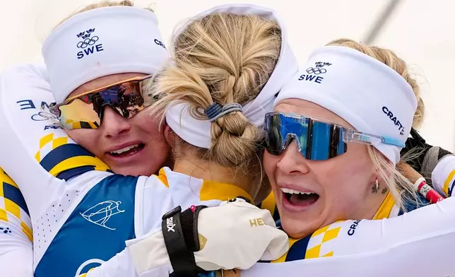 Gold medalist Linn Svahn, of Sweden, center, hugs silver medalist Jonna Sundling, right, and bronze medalist Maja Dahlqvist, both also of Sweden, after the cross-country skiing women's sprint classic at the 2026 Winter Olympics, in Tesero, Italy, Tuesday, Feb. 10, 2026. (AP Photo/Matthias Schrader)
