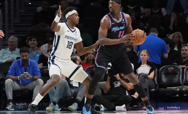 Memphis Grizzlies forward Olivier-Maxence Prosper (18) defends Miami Heat center Bam Adebayo (13) during the first half of an NBA basketball game, Saturday, Feb. 21, 2026, in Miami. (AP Photo/Lynne Sladky)