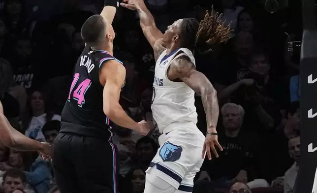 Miami Heat guard Tyler Herro (14) shoots as Memphis Grizzlies guard Javon Small, right, defends during the first half of an NBA basketball game, Saturday, Feb. 21, 2026, in Miami. (AP Photo/Lynne Sladky)