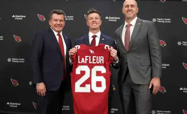 Arizona Cardinals new head coach Mike LaFleur, center, poses with owner Michael Bidwell, left, and general manager Monti Ossenfort during an NFL football news conference, Tuesday, Feb. 3, 2026, in Tempe, Ariz. (AP Photo/Rick Scuteri)