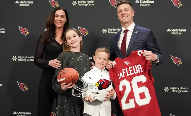 Arizona Cardinals new head coach Mike LaFleur poses with his family after after being introduced during an NFL football news conference, Tuesday, Feb. 3, 2026, in Tempe, Ariz. (AP Photo/Rick Scuteri)