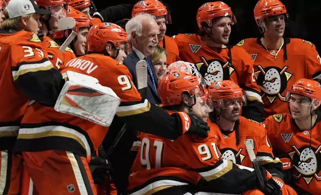 Anaheim Ducks head coach Joel Quenneville, center, poses with players and family after winning his 1,000th career coaching victory with a 6-4 win over the Edmonton Oilers in an NHL hockey game Wednesday, Feb. 25, 2026, in Anaheim, Calif. (AP Photo/Gregory Bull)