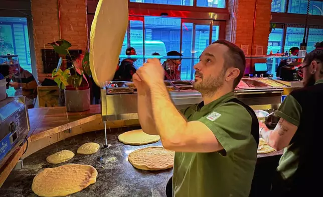 A chef of the Neverland Pizzeria makes dough for the restaurant's Roman-era pizza in Budapest, Hungary, on Feb. 11, 2026. (AP Photo/Bela Szandelszky)