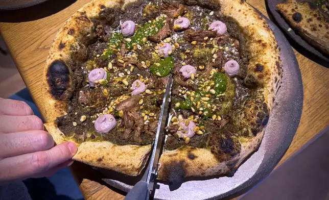 A customer cuts a Roman-era pizza in Budapest, Hungary, on Feb. 11, 2026. (AP Photo/Bela Szandelszky)