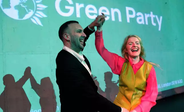 Green Party candidate Hannah Spencer, right, celebrates with party leader Zack Polanski at a volunteer thank you event after winning the Gorton and Denton by-election, Manchester, England, Friday, Feb. 27, 2026. (AP Photo/Jon Super)