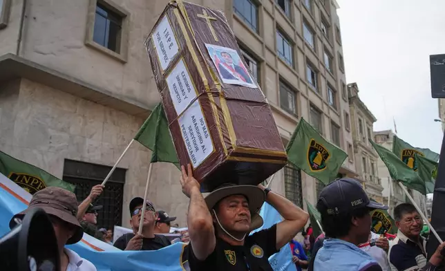 A demonstrator carries a fake coffin with a photo of interim President Jose Jeri after Congress voted to remove him, outside the site where lawmakers met in Lima, Peru, Tuesday, Feb. 17, 2026. (AP Photo/Guadalupe Pardo)