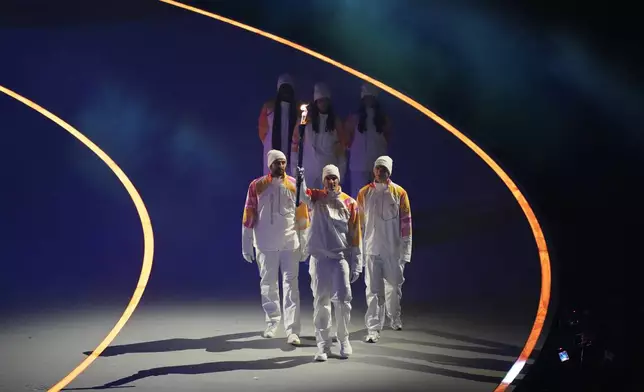 The Olympic torch is carried during the Olympic opening ceremony at the 2026 Winter Olympics, in Milan, Italy, Friday, Feb. 6, 2026. (AP Photo/Stephanie Scarbrough)